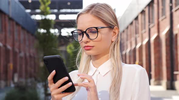 Confident Freelancer Stands in Business District Uses Phone Scrolling Internet