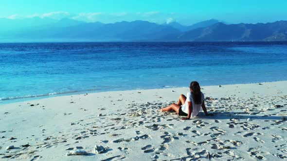 Ladies tan on marine resort beach vacation by shallow ocean with bright sandy background of Gili Air