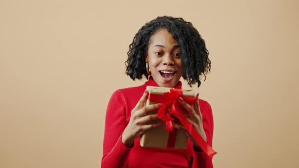 Young Happy African American Woman Catching Gift Box Enjoying Surprising Present Smiling to Camera