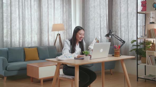 Female Footwear Designer Holding The Colourful Pattern Sneaker And Comparing To Pictures On Laptop