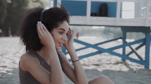 Beautiful African American Woman on a Summer Beach Vacation Using a Headphones to Listen Music By