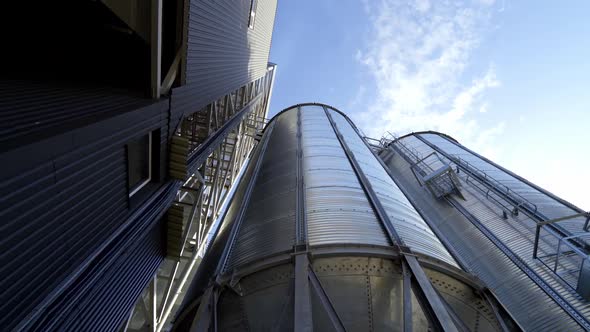 Modern granary under blue sky. Large aluminum containers for storing grains