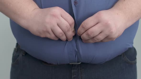 Fat Man Making Lot of Effort to Button Up His Shirt on Huge Paunch, Obesity