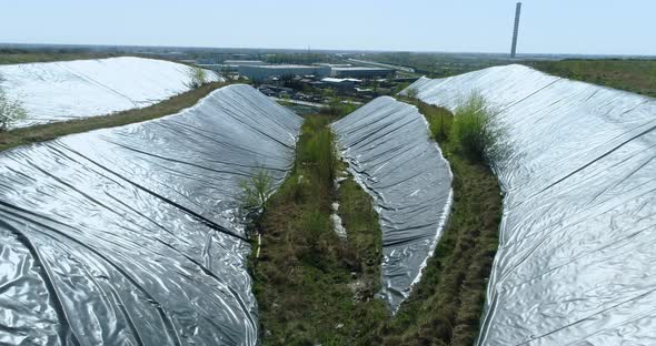 Aerial view of the sides of garbage dump hill covered with protective film.