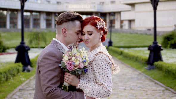 Beautiful Couple of Bride and Groom Hug in Park