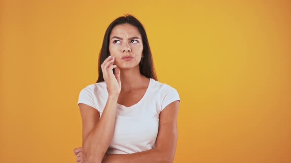 Thoughtful Woman Raising Up Forefinger Like Got an Idea and Smiling Posing on Orange Background