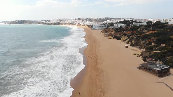 Mediterranean Beach line on sunny day in Albufeira, Algarve, Portugal - Fly-over Aerial shot
