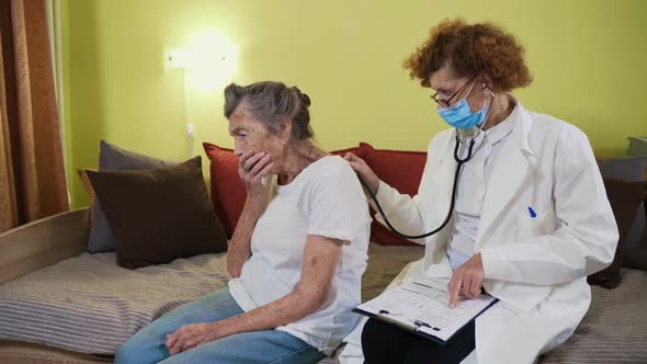 Elderly Caucasian Woman Doctor Listening To Elderly Patient Breathing Medical Exam with Stethoscope