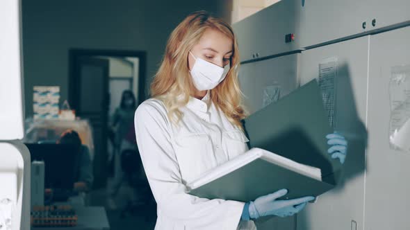 Portrait of a Lab Worker with a Research Folder in Her Hands. Ladorant Reviews Research Records in