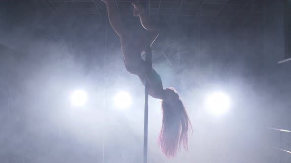 Dance and Acrobatics Concept. Sexy Woman Pole Dancing in Dark Interior with Lights and Smoke