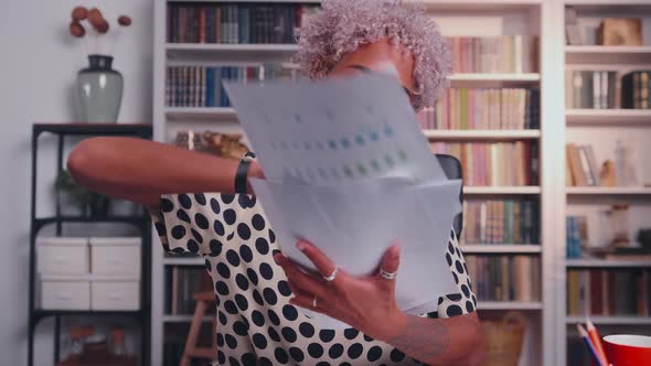 African American Woman Smiles and Scatters Business Documents Sits in Office