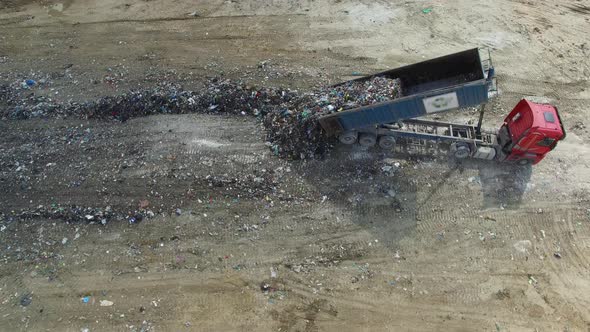 A landfill lorry is unloading garbage into junkyard. Aerial vertical shot