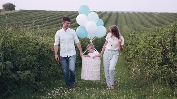 Father and Mother Are Carriyng a Son in a Basket with Baloons