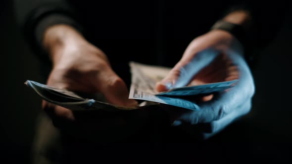 Man's Hands Is Counting One Hundred Dollar Bills on a Dark Background.