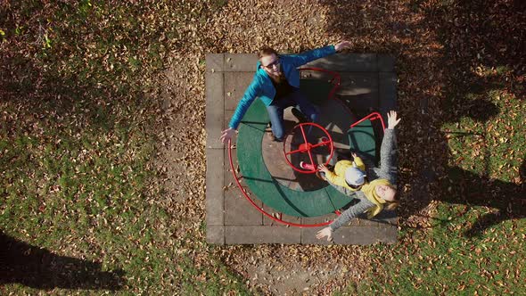 Aerial view of family spinning at merry-go-round with the arms open, Croatia. alt