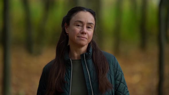 Portrait of a Middle-aged Woman with Dark Hair Enjoying Nature in an Autumn Forest. Smiling and