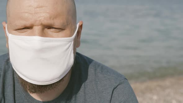 Unhappy Bold Man Close Up Portrait Wearing Medical Face Mask in Public Beach Places