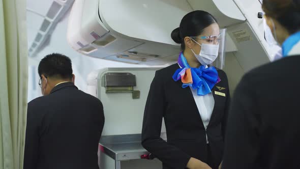 Asian flight attendants people wearing face mask greeting passengers walking on board in airplane.