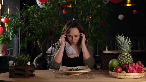 a Girl in a Cafe Takes Off Her Mask to Eat