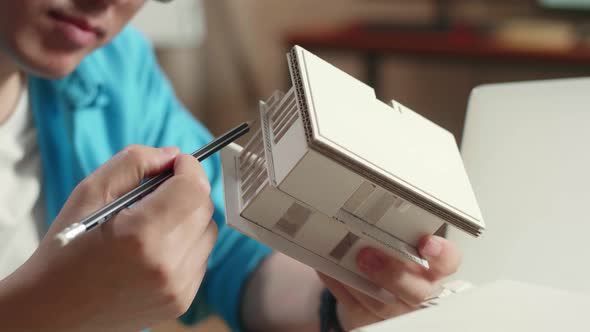 Close Up Of Hand's Man Engineer Holding Paper Model Of House At The Office