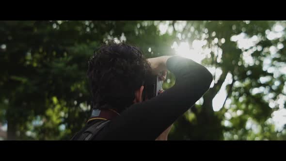 Man taking pictures of the light shining through the trees