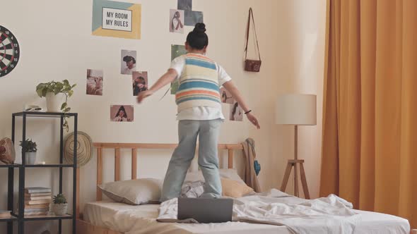 Asian Teenage Girl Jumping on Bed