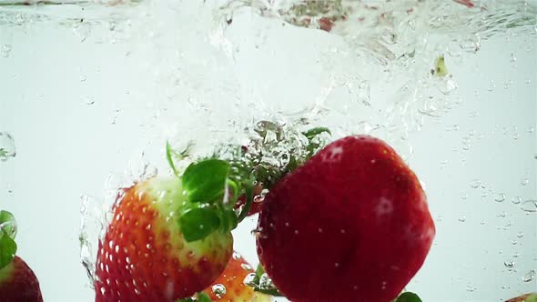 Ultra Slowmo Multiple Strawberries Splashed into Water on White Background