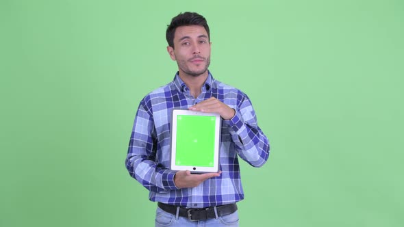 Happy Young Hispanic Man Talking While Showing Digital Tablet