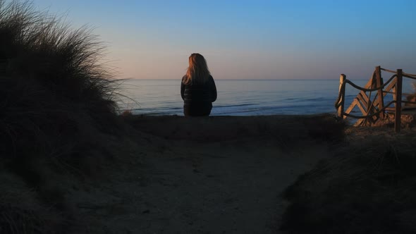 Shot of a Woman Sitting on a Log Overlooking the Beautiful Coast of Denmark