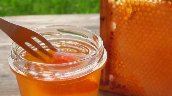 Closeup of the Piece of Red Strawberry on the Fork Dipped Into Delicious Honey