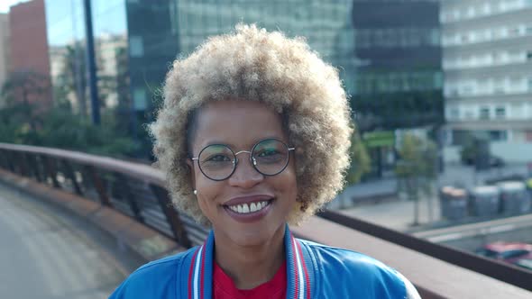 African American Woman with Afro Hair Looking at Camera in a City