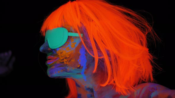 A Girl with an UV Pattern on Her Face Wearing an Orange Wig and Green Glasses