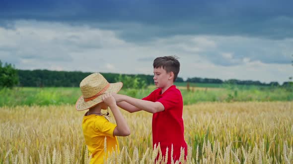 Elder brother puts straw hat on younger kid head