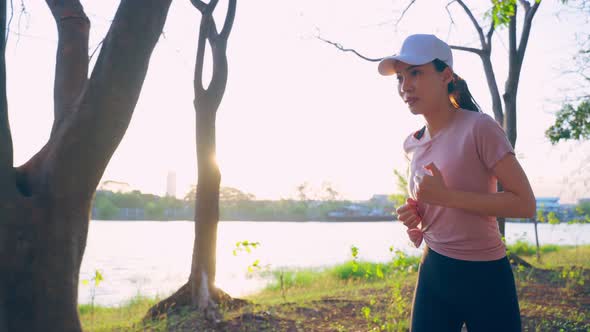 Asian young beautiful sport woman running on street in public park.