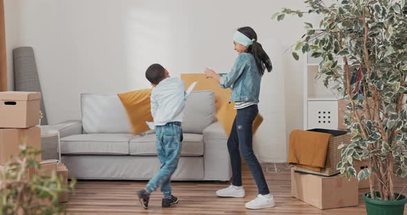 Siblings are Playing in the Living Room After Moving Into a New Apartment Cardboard Boxes with