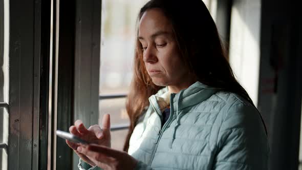 Female Passenger of Suburban Train with Smartphone Using Social Media