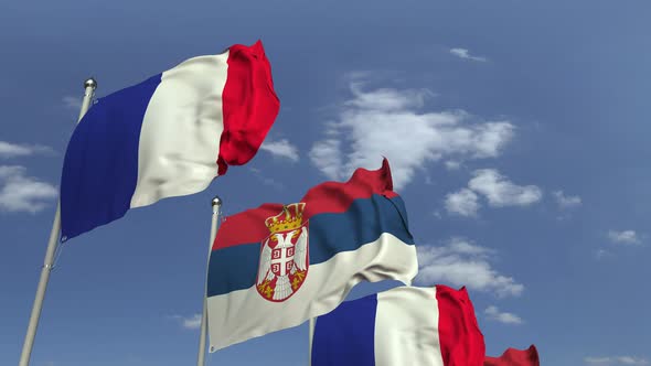 Waving Flags of Serbia and France on Sky Background alt