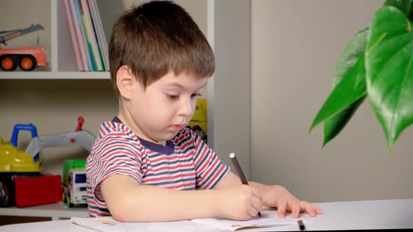 A Child of 4 Years Old Learns to Write Copybook Sits Correctly at the Table