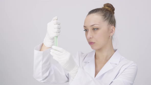 Female Research Scientist Shaking Yellow Green Chemical Liquid in Test Tube