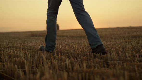 Farmer Boots Walk Field with Haystack at Golden Sunset Closeup