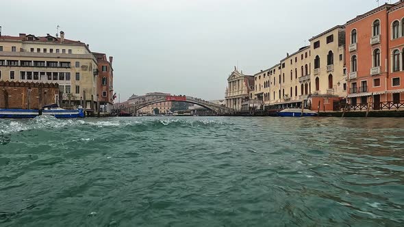 Water surface pov of Venice seen from ferry boat on Canal Grande with Ponte Degli Scalzi bridge in b