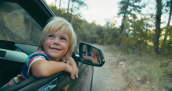 Happy Children on Vacation Road Trip Look Out From Vehicle Window on Forest Road