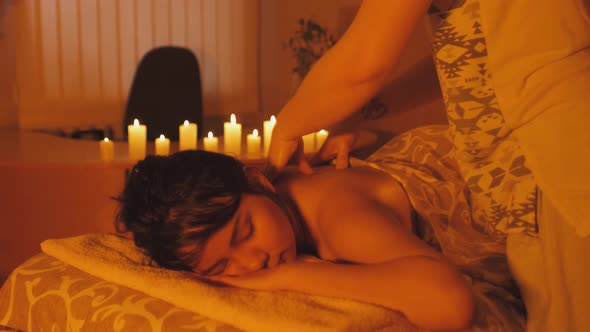 Mixed Race Ecuadorian Woman Enjoying Body Massage in Spa Salon with Candle Light