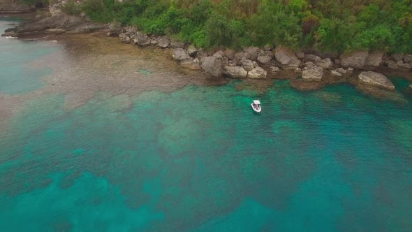 Pull Back Aerial View on Solitary Boat Anchored in Tropical Lagoon of Exotic Island