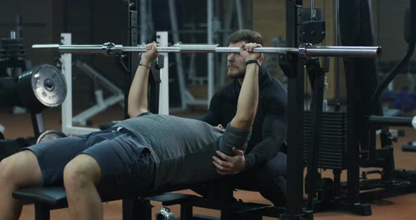 Trainer Overseeing Young Man Doing Bench Press