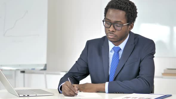 African Businessman Writing Letter in Office