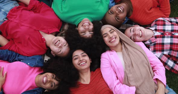 Group of multiracial female friends lying on grass and having fun together