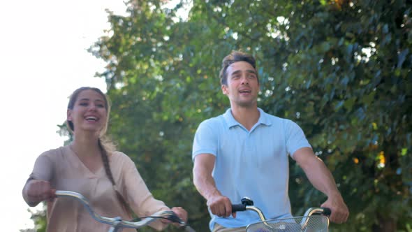Happy Young Couple on Bicycles on a Background of Green Trees