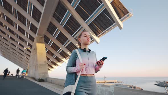 Millennial Female Marching Alone Embankment After Jogging Looking on Phone