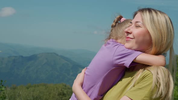 Joyful Woman Holds Little Daughter Against Old Mountains